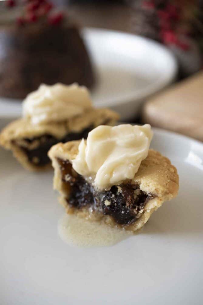 A Christmas mince pie cut in half with brandy butter melting over.