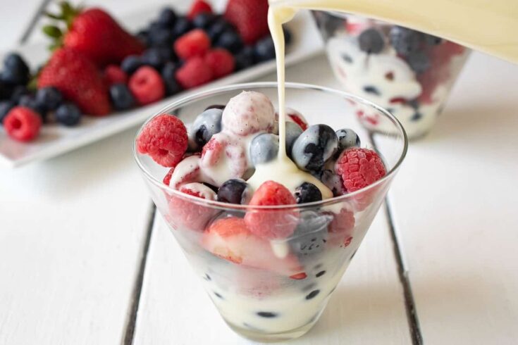 Frozen berries in a glass bowl with vanilla custard