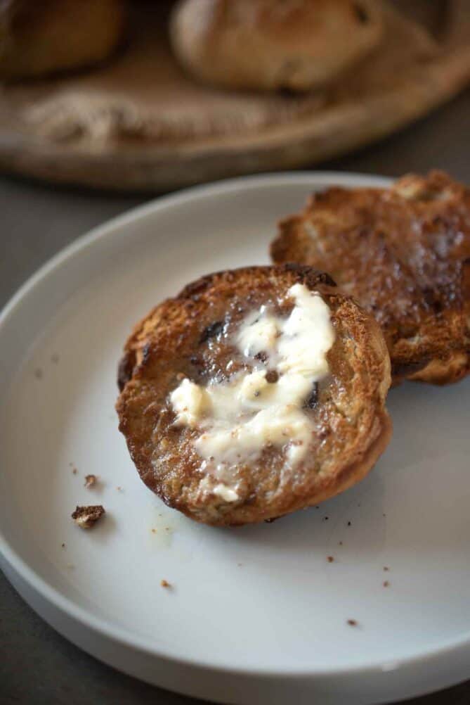 Half of a currant teacake topped with melting butter