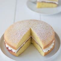 A whole Victoria Sponge Cake with a piece removed