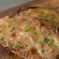 A closeup of melted beer and cheese sauce on top of crusty bread slices topped with chopped chives