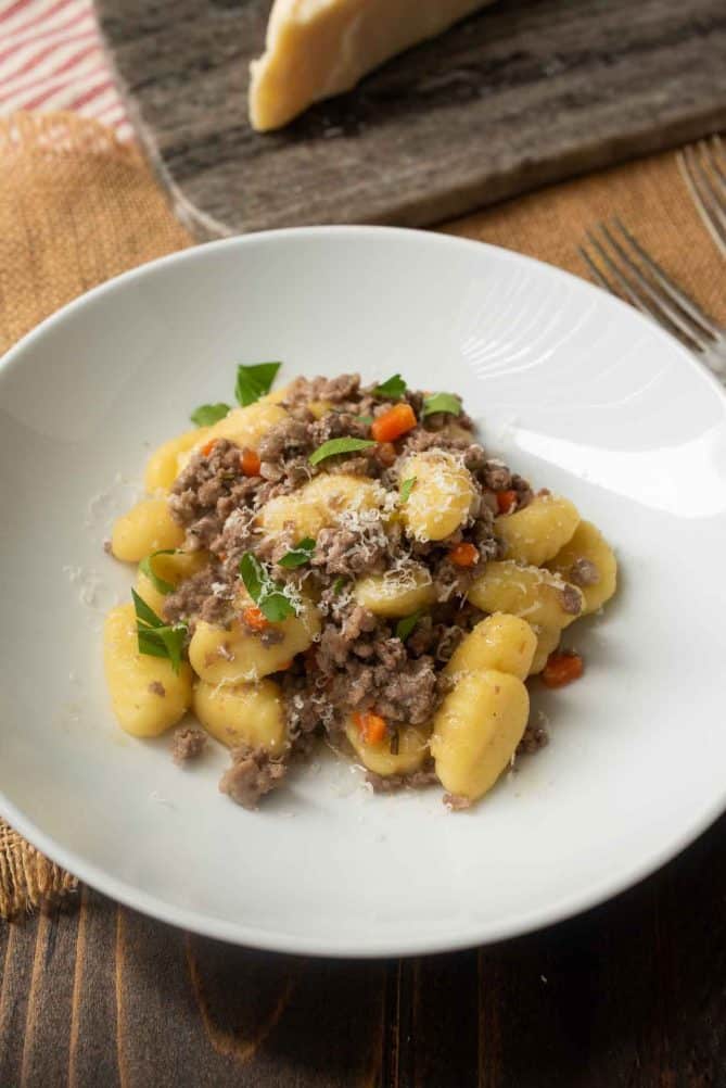 Bolognese sauce mixed with gnocchi in a white bowl