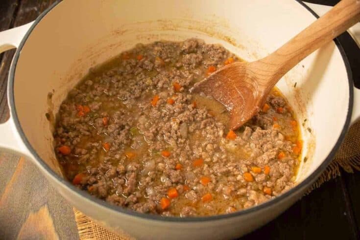 Meaty white Bolognese sauce in a white Dutch oven