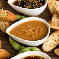 Savory and sweet Asian sauces surrounded by spring rolls
