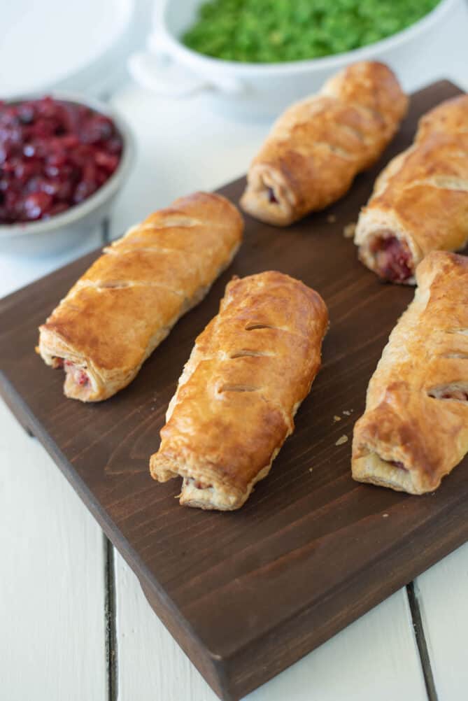 Golden brown pastry sausage rolls on a board
