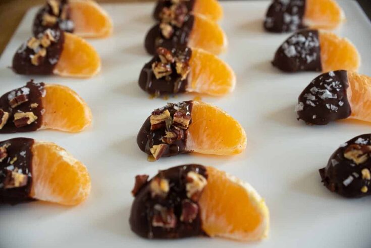 Juicy orange segments, half covered in chocolate, pecans, flaky salt and caramel sauce