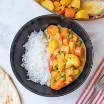 A black bowl filled with white rice and vegetable curry