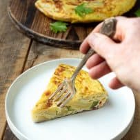 Cutting a bite with a fork from a slice of vegetable Spanish omelette tortilla