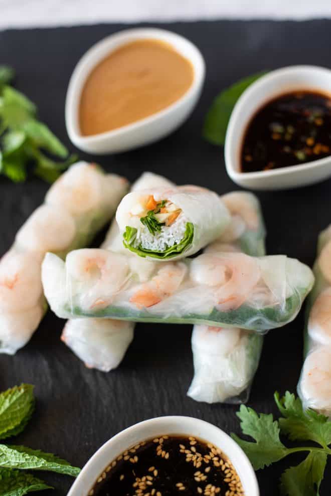 A roll cut in half showing the noodles, lettuce, carrots and shrimp inside.