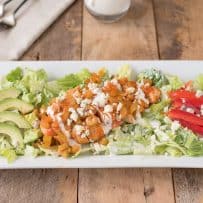A warm buffalo chicken salad on a white rectangle plate