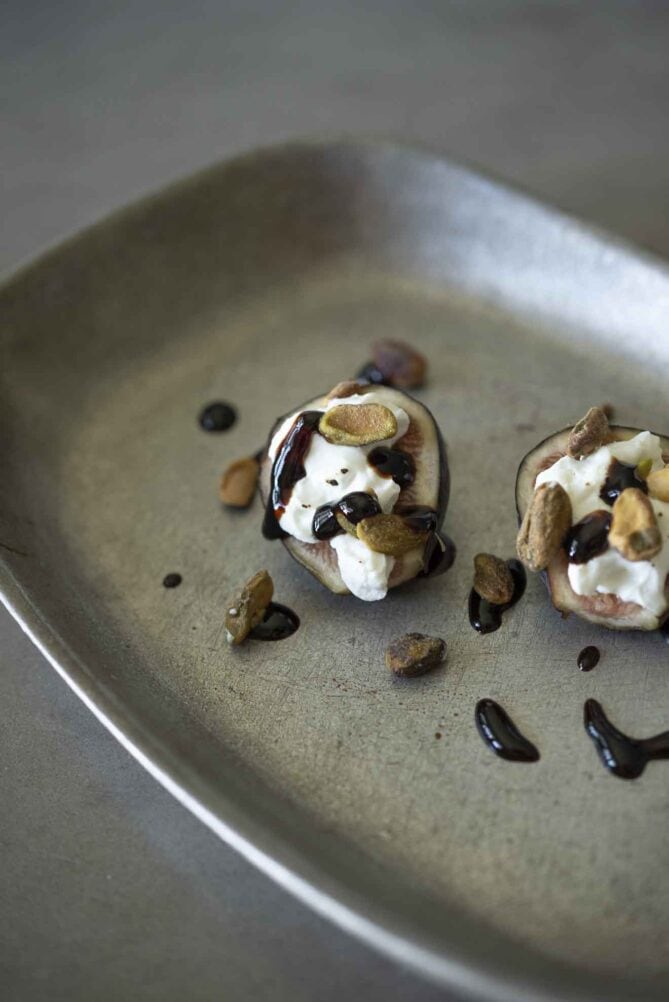 Halved figs topped with goat cheese, pistachio nuts and balsamic glaze