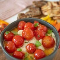 A bowl of ricotta and goat cheeses topped with tomatoes