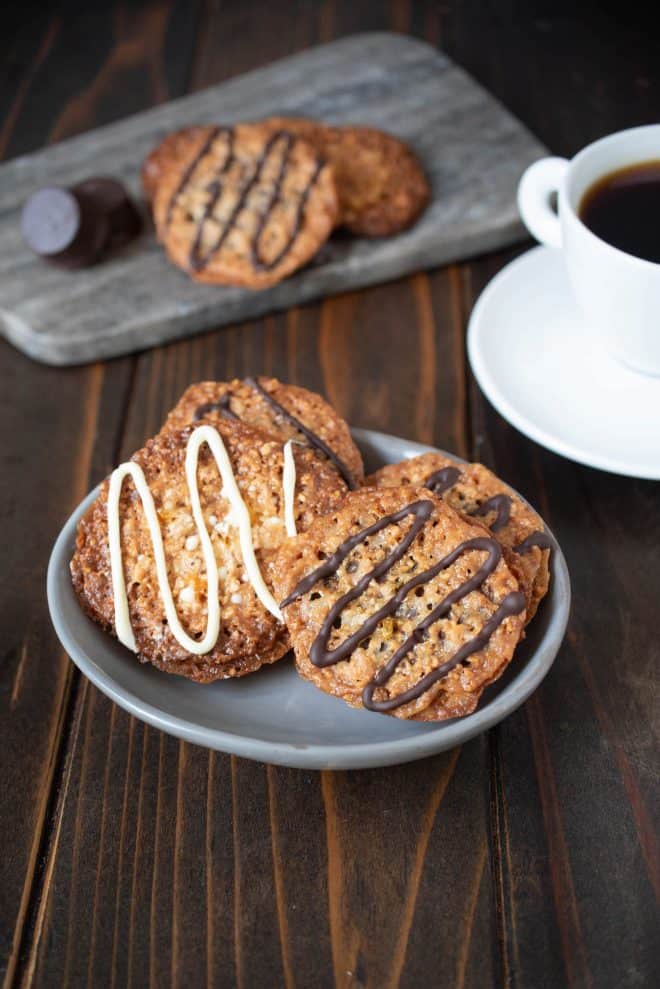 A white chocolate Florentine and dark chocolate Florentine cookie on a grey plate