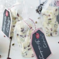 White Chocolate Pistachio Cranberry Fudge Squares wrapped in clear bags with Happy Holidays gift tags