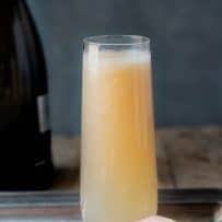 A beautiful peach hue color Bellini cocktail in a serving tray with white peach halves