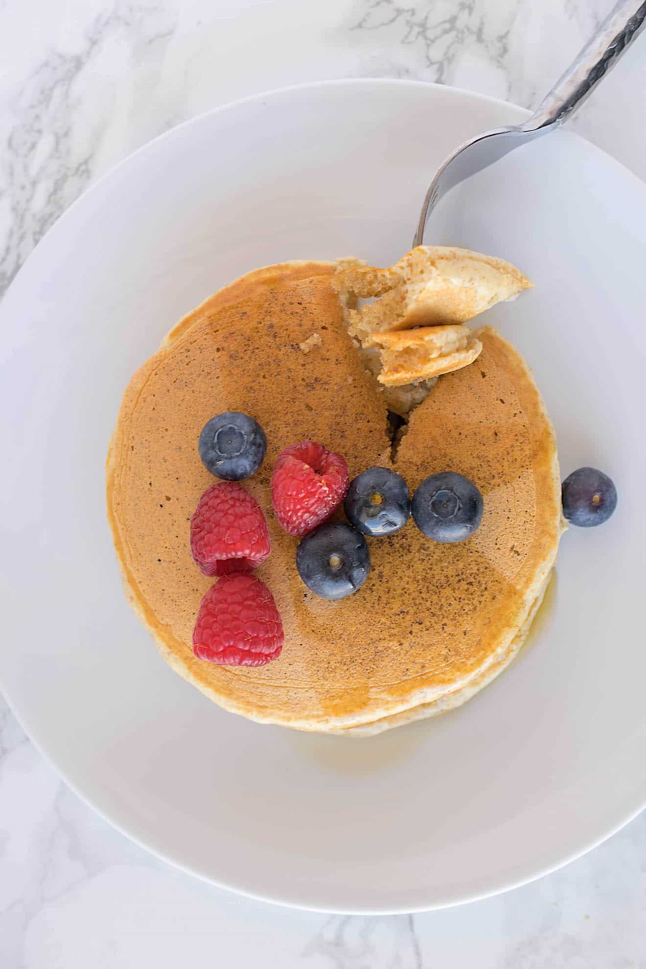 Cutting a piece of pancake with a fork, viewed from overhead
