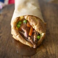 The end view of a Yorkshire burrito with gravy oozing out from roast beef, carrots and peas
