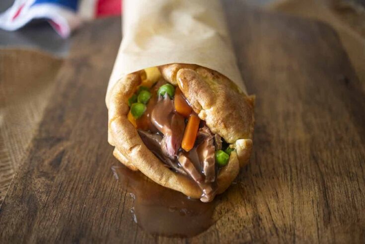 The end view of a Yorkshire burrito with gravy oozing out from roast beef, carrots and peas