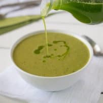 Drizzling basil oil on top of the soup