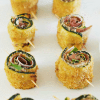 2 rows of baked zucchini rolls on a white serving plate