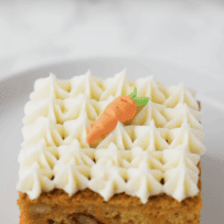 A sugar carrot on top of a square slice of carrot cake