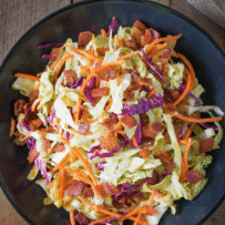 Green and red shredded cabbage and carrot coleslaw mixed with crispy bacon pieces
