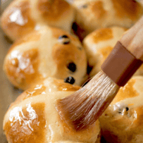 Rows of lemon hot cross buns with dried blueberries