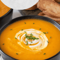 Bright orange carrot soup with a swirl of sour cream and chopped chives