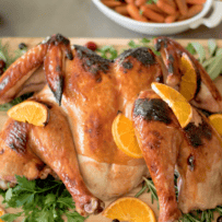 An orange cranberry glazed spatchcock turkey on a cutting board
